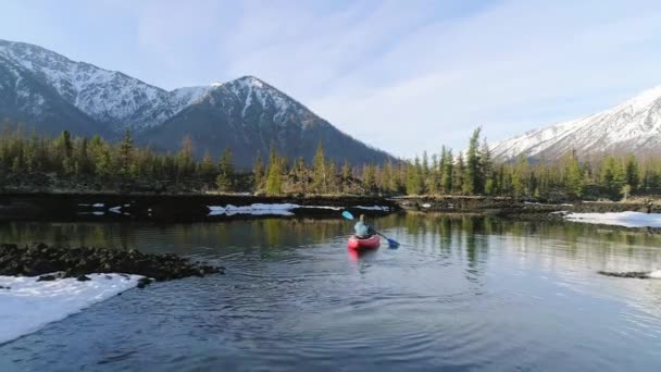 Touristen segeln auf einem Kanu im See in Richtung der Berge im Tal. Antenne. — Stockvideo