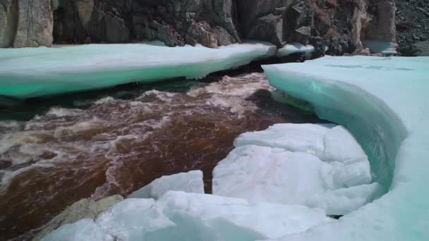Derretimiento de hielo en el río que fluye rodeado de roca — Vídeo de stock