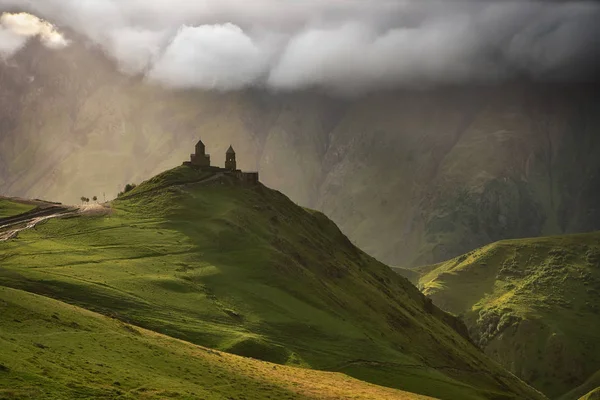 Gergeti Trinity Kilisesi yapraklara Gürcistan'daki Kazbegi Dağı ile güneş doğarken