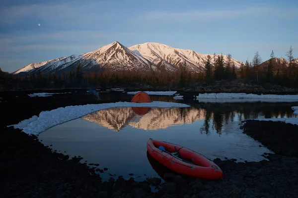 Campingplats med orange tält och kanot på en sjö — Stockfoto