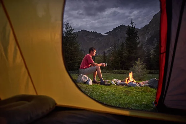 Blick aus dem Inneren des Touristenzeltes bei Sonnenuntergang. Einsamer Tourist, Wandersmann am Lagerfeuer — Stockfoto