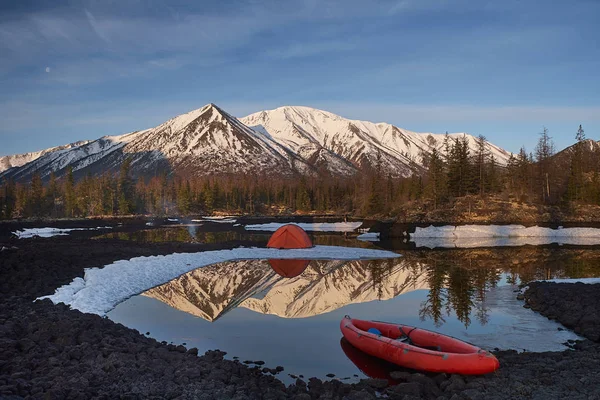 Campingplats med orange tält och kanot på en sjö — Stockfoto