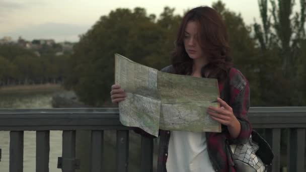 Mooie jonge vrouw met toeristische kaart op zoek lopen in de stad straat. — Stockvideo