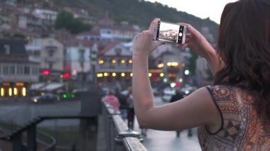 Kadın turist alma eski şehrin sokak ışıkları ile cep telefonu tarafindan fotograf