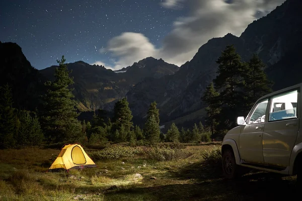 Acampar com um carro, tenda amarela à noite com luar na área da montanha — Fotografia de Stock