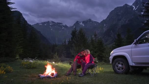 Time-lapse de pareja charlando por hoguera en camping en valle de montaña. puesta de sol — Vídeo de stock