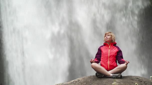 Mujer haciendo yoga pose loto frente a gran cascada — Vídeo de stock