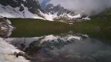 dağlarla çevrili berrak bir gölün timelapse. Bulutlar dalgalanıyor