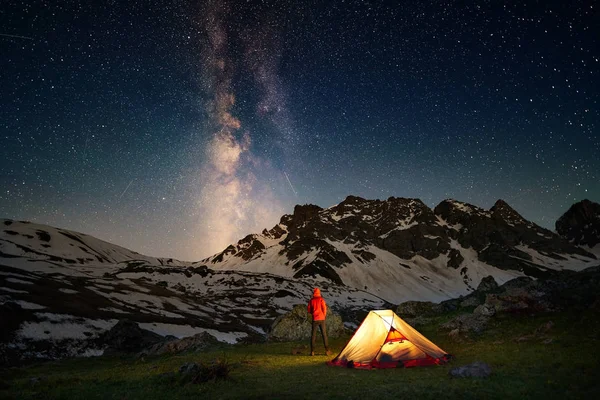 Hiker stoi w pobliżu namiotu i patrząc na drogę mleczną w górach w nocy — Zdjęcie stockowe