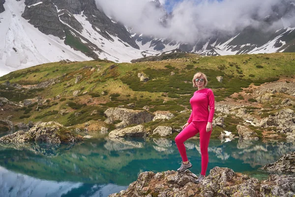 Hiking woman in red jacket stay at beautiful turquoise lake in mountains. — Stock Photo, Image