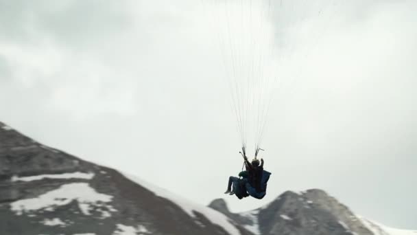 Camera following paraglider flying over snowy mountains — Stock Video