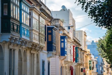 Sıcak sokak ve Sliema 'da geleneksel renkli ahşap balkonlar.,