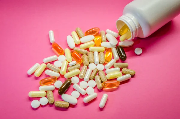 Karışık ilaç hapları, haplar, kapsüller ve şişe pembe bir torbaya.