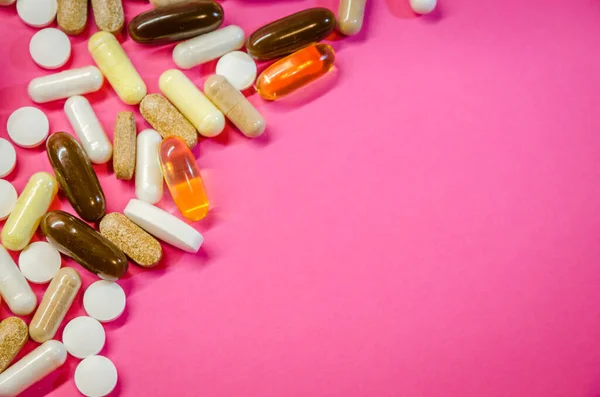 Pembe arka planda ilaç, hap ve kapsüller var..