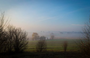 Kırsalda sabah sisi sisi. Sahada gün doğumu zamanı. Nehir sabah sisinin altında.