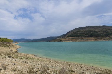 Göl manzarası, dağlar ve gökyüzü güneş ve bulutlarla