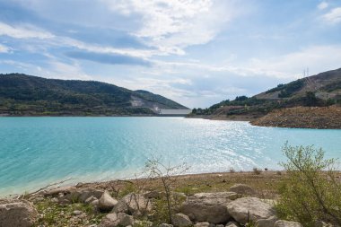Göl manzarası, dağlar ve gökyüzü güneş ve bulutlarla