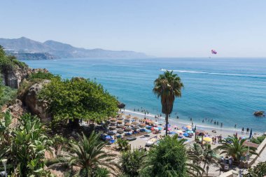 Sahil, deniz, banyo yapan ve su sporları yapan insanlar. Bir motorlu tekne tarafından çekilen paraşüt.