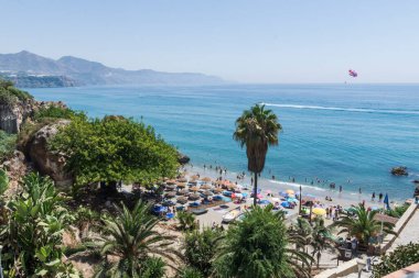 Sahil, deniz, banyo yapan ve su sporları yapan insanlar. Bir motorlu tekne tarafından çekilen paraşüt.