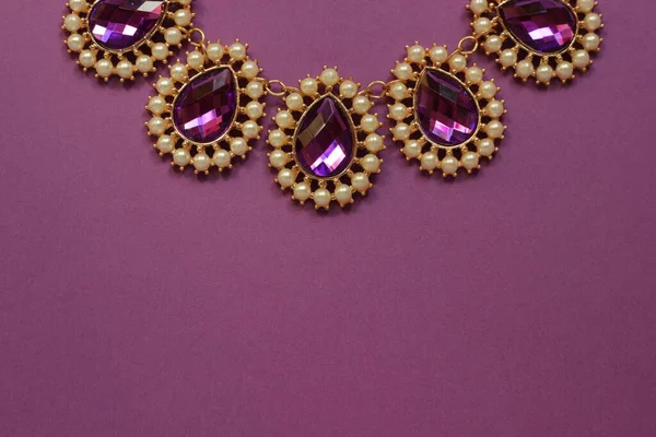 luxury green jewelry in the Baroque style on a purple background. Vintage, retro style.