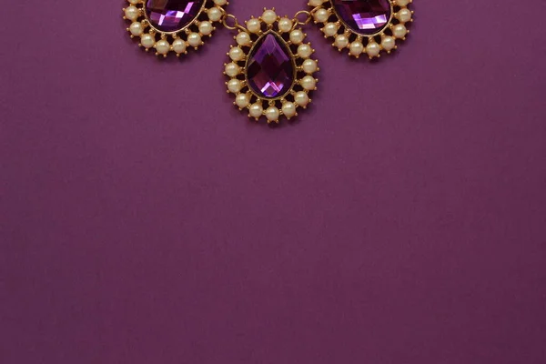 luxury green jewelry in the Baroque style on a purple background. Vintage, retro style.