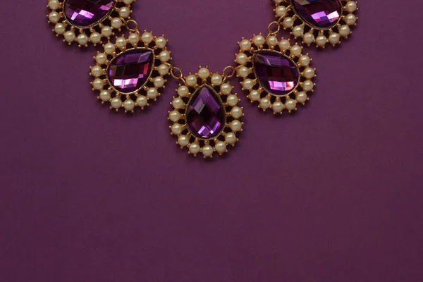 luxury green jewelry in the Baroque style on a purple background. Vintage, retro style.