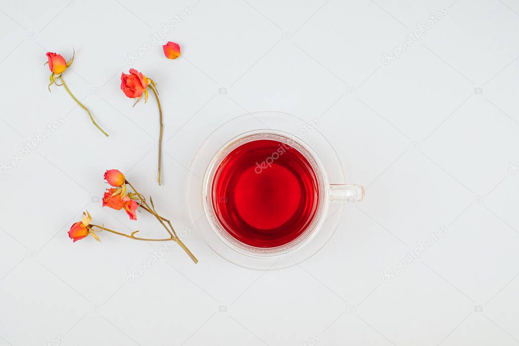 Cup of tea and roses on white background top view