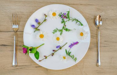 Tabakta bahar çiçekleri, çatal ve kaşık. Ahşap arka plan. Üst Manzara. Sağlıklı gıda konsepti
