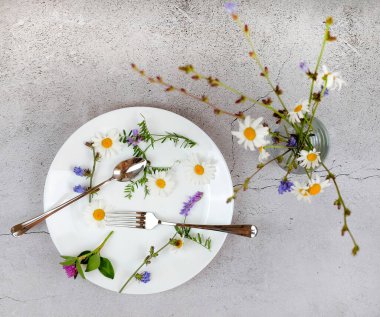 Tabakta papatya ve yabani çiçekler. Gri desenli arka plan. Bahar ve yaz konsepti. Saf doğa. Kare resim.