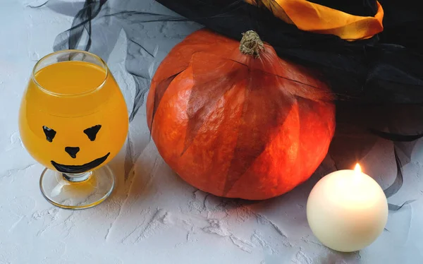 Хэллоуинская композиция с напитком, апельсиновым коктейлем, тыквой, свечой и шляпой — стоковое фото