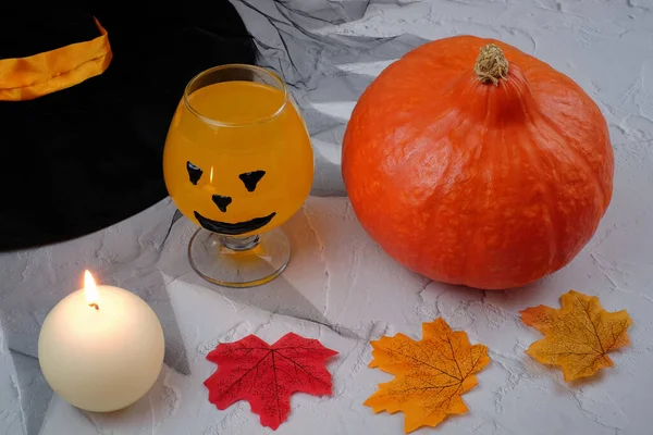 Хеллоуїн композиція з напоєм, апельсиновий коктейль, гарбуз, свічка, капелюх і опале листя — стокове фото