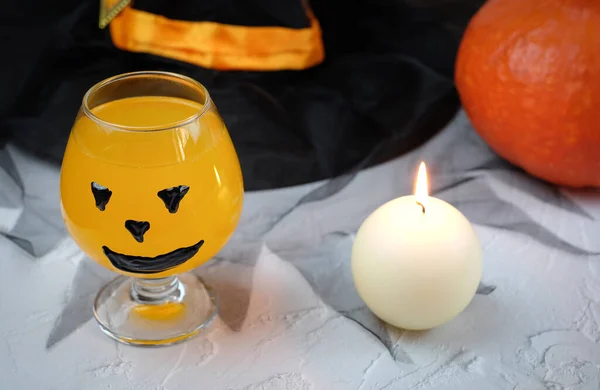 Хэллоуинская композиция с напитком, апельсиновым коктейлем, тыквой, свечой, шляпой. Селективный фокус — стоковое фото