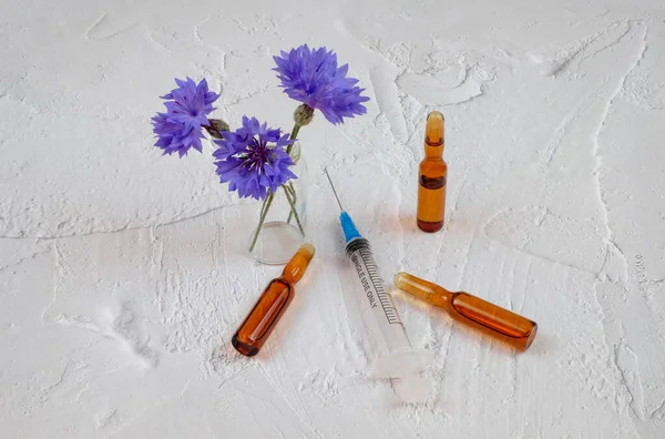 Composition with ampules, medical syringe, and flowers — Stock Photo, Image