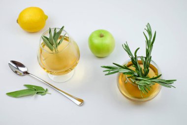 Bardakta biberiye çayı, limon, elma ve çay kaşığı.