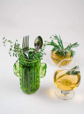 Cam fincanlarda biberiye çayı, beyaz arka planda kekik ve çatal.