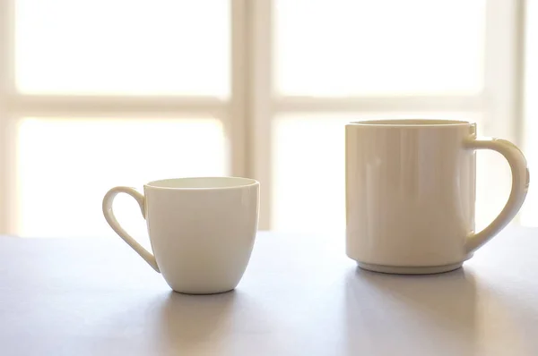 Two white cups of coffee on kitchen defocused background