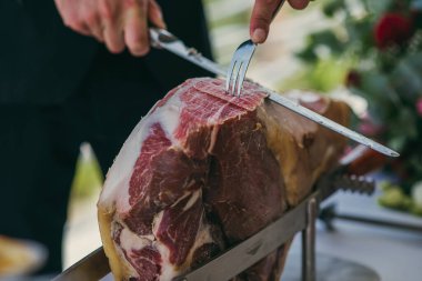 Zarif bir restoranda ya da yemek servisinde bir garson tarafından bıçakla dilimlenmiş çiğ jambonla kapat..