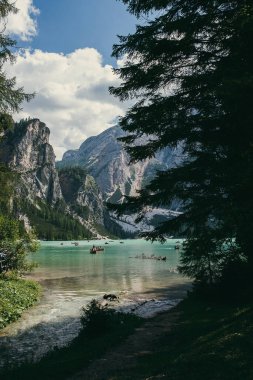 Dikey görüntü. Dağ manzaralı göl, kayalıklar, kayıklar ve ağaçlar.