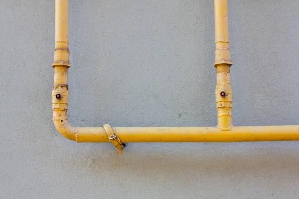 Yellow gas pipe in front of  building wall