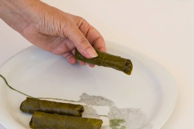 El sarma, beyaz tabakta ıslak üzüm yaprakları yuvarlama, geleneksel Türk yemeği hazırlama, yukarıdan bakıldığında