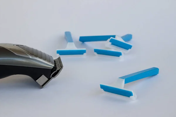 Gri arka planda paslanmaz çelik bıçakları ve mavi jiletleri olan ince saçlı kırpıcı..