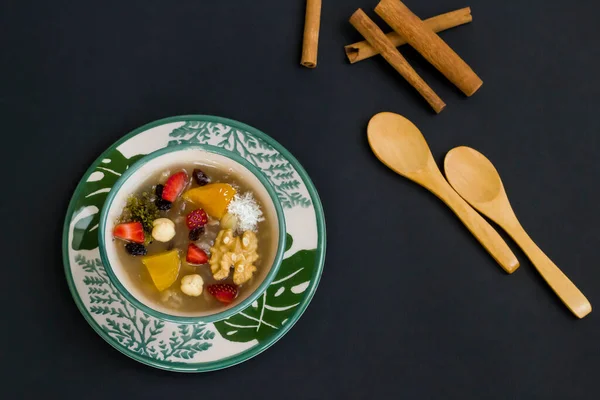 Geleneksel Türk Tatlısı Nuh 'un Puding' i siyah yüzey üzerinde kaşık ve kopyalama alanı ile süslü yeşil kase..