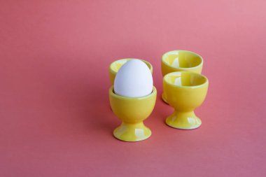 Sarı yumurta tutacağında beyaz bir yumurta ve pembe arka planda boş tutacakları var..