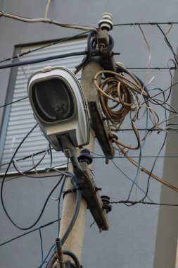 Bina yakınında birbirine dolanmış bir sürü kabloyla sokak lambası direği, dikey görüntü.
