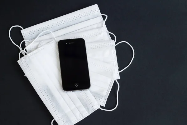 Siyah üzerine beyaz renkli cep telefonlu tıbbi maskeler. TR 'de ödeme yapmadan kod numarasıyla maske takmak mümkündür.