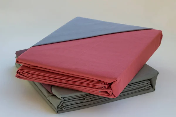 Kullanılmamış, yeni, çift renkli yatak örtüsü ya da açık renk arka planda katlanmış yorgan örtüsü..