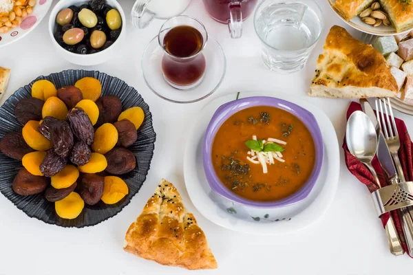 Geleneksel Türk Ramazan Yemeği çorba, ekmek, su, kuru yaş meyveleri ve kumaş peçetede zeytin.
