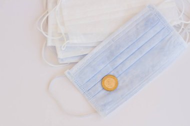 Beyaz yüzeyde tek kullanımlık hijyenik, tıbbi yüz maskeleri ve bir Türk lirası..