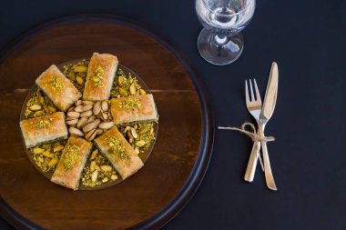Geleneksel Türk Pastası Tatlısı, Pistachio Baklava ve çatal bıçak takımı ve bir bardak su. Bayramların kavramsal görüntüsü.