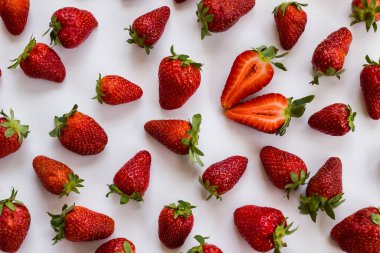 Beyaz yüzeyde taze, olgun çilekler, bir dilimlenmiş, düz bir düzen, arka planlar.